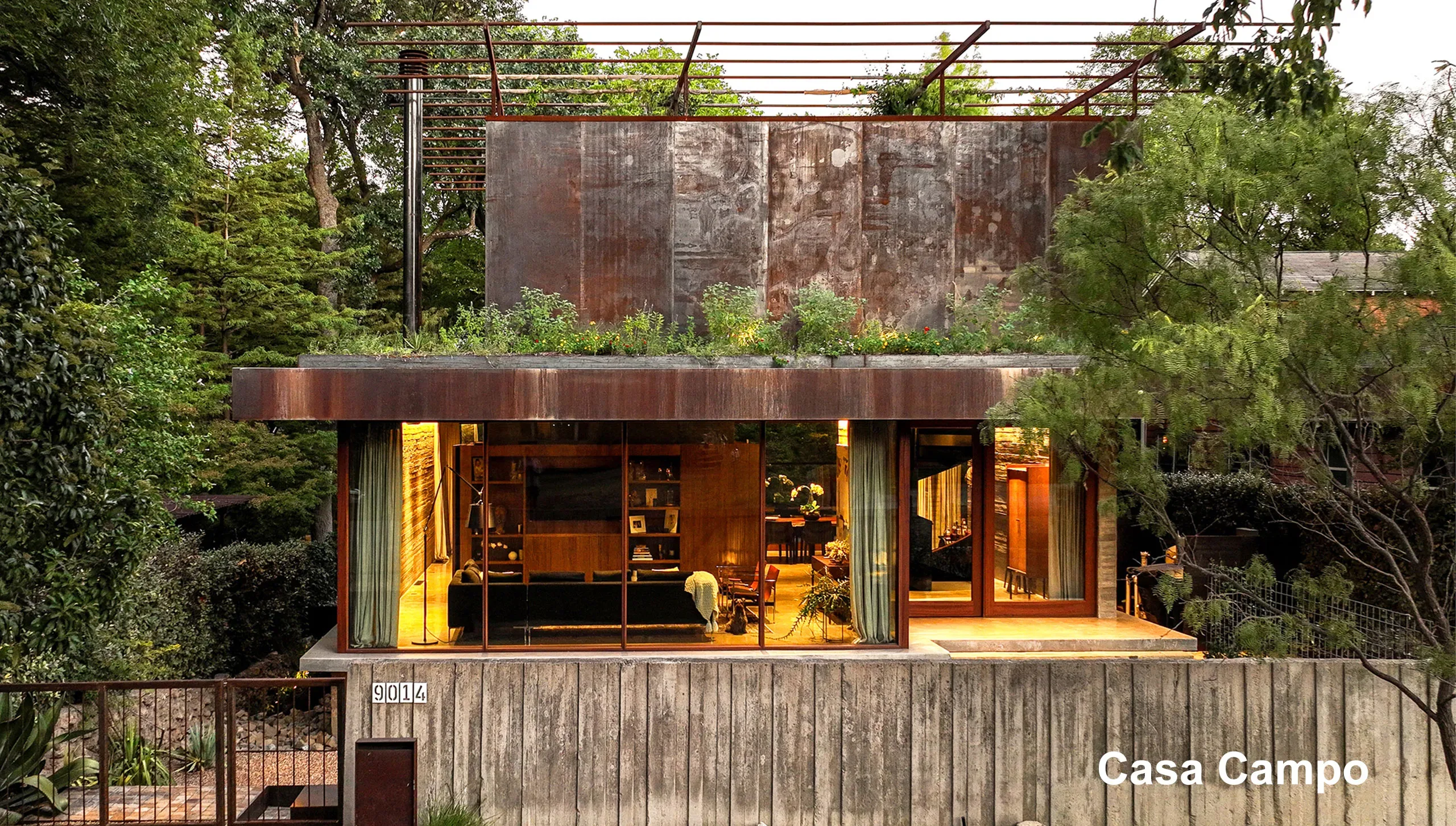 A house with a green roof in the middle of a wooded area.